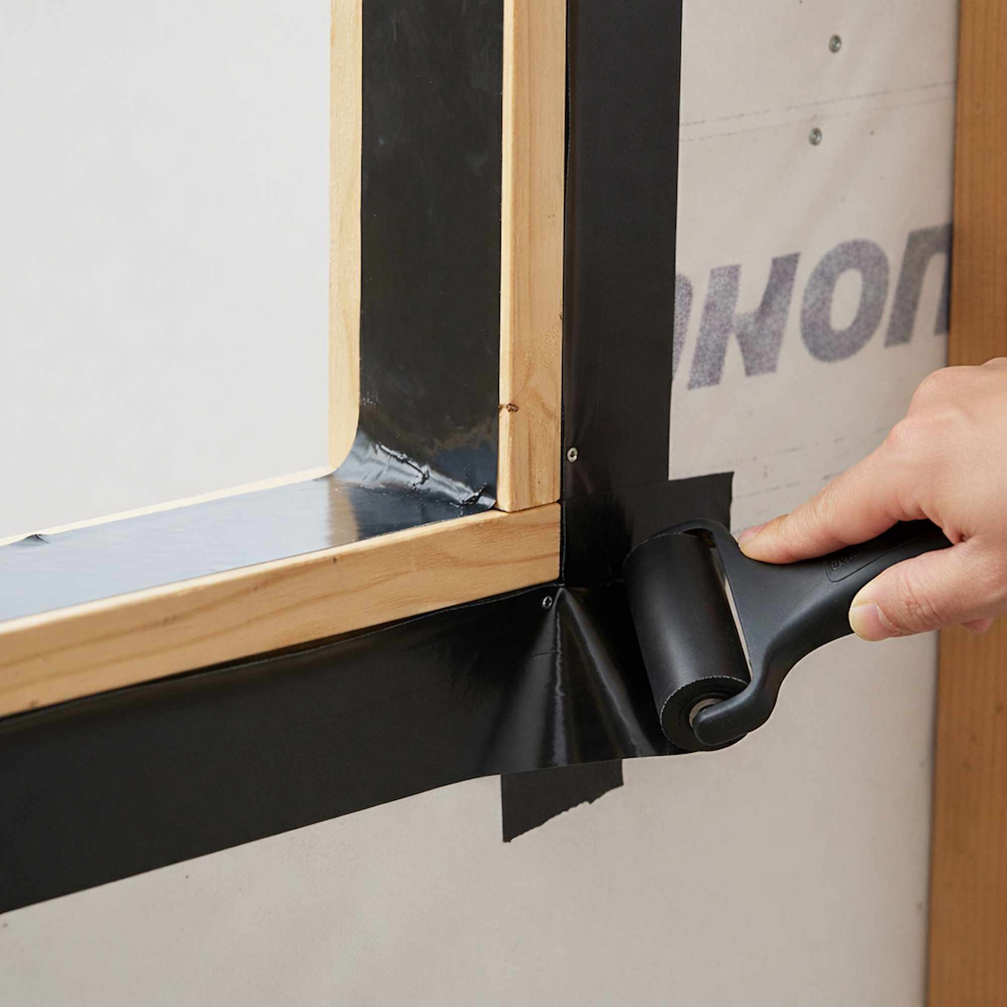 Close-up of butyl flashing tape applied to window frame corner for exterior waterproofing